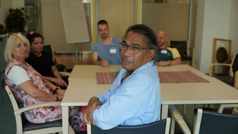 Ein Mitarbeiter blickt in die Kamera an einem Tisch mit mehreren Personen im Hintergrund bei einer Besprechung in der Klinik für Psychiatrie und Psychotherapie im Albertinen Krankenhaus in Hamburg. Ein Mitarbeiter blickt in die Kamera an einem Tisch mit mehreren Personen im Hintergrund bei einer Besprechung in der Klinik für Psychiatrie und Psychotherapie im Albertinen Krankenhaus in Hamburg.