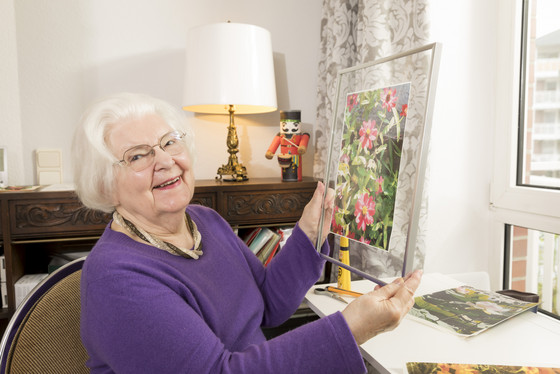 Eine Seniorin schaut sich ein eingerahmtes Bild an, Freizeitangebot in der Seniorenresidenz, Freizeitkurse für Senioren und Seniorinnen, Residenz am Wiesenkamp, Hamburg-Volksdorf