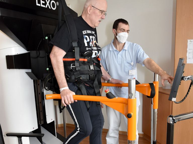 Patient auf Gangtrainer in Begleitung eines Physiotherapeuten - Interdisziplinäres Therapiezentrum - Neurologie - Albertinen Krankenhaus Hamburg Patient auf Gangtrainer in Begleitung eines Physiotherapeuten - Interdisziplinäres Therapiezentrum - Neurologie - Albertinen Krankenhaus Hamburg