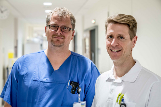 Zwei Ärzte lächeln in einem Krankenhausflur in die Kamera, Albertinen Krankenhaus, Abteilung Anästhesiologie und Intensivmedizin